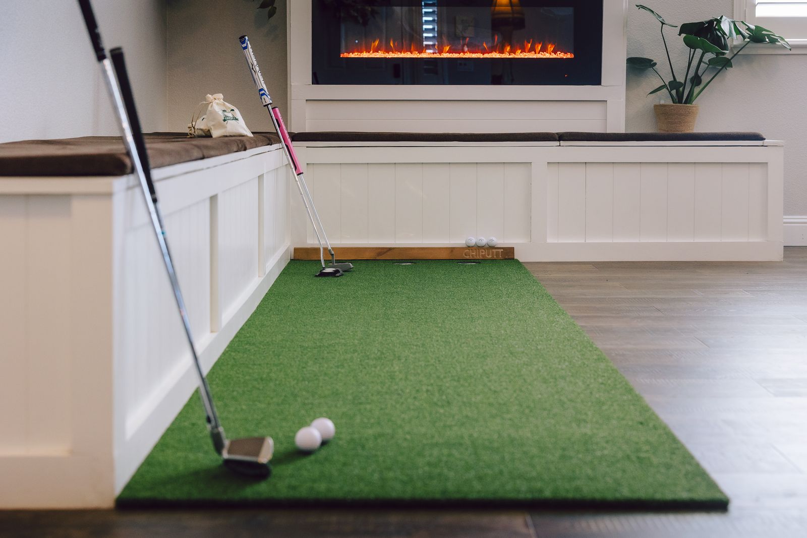 Cozy indoor putting green setup with a fireplace in the background