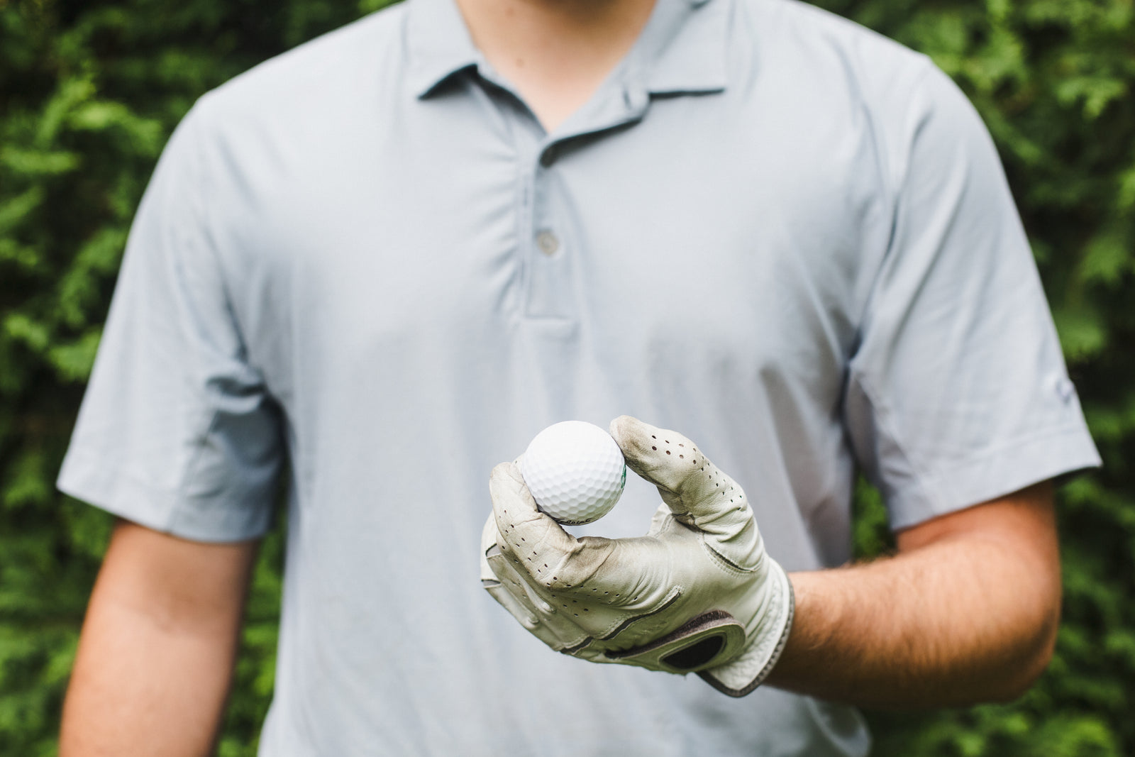 Golfer holding a golf ball in a gloved hand