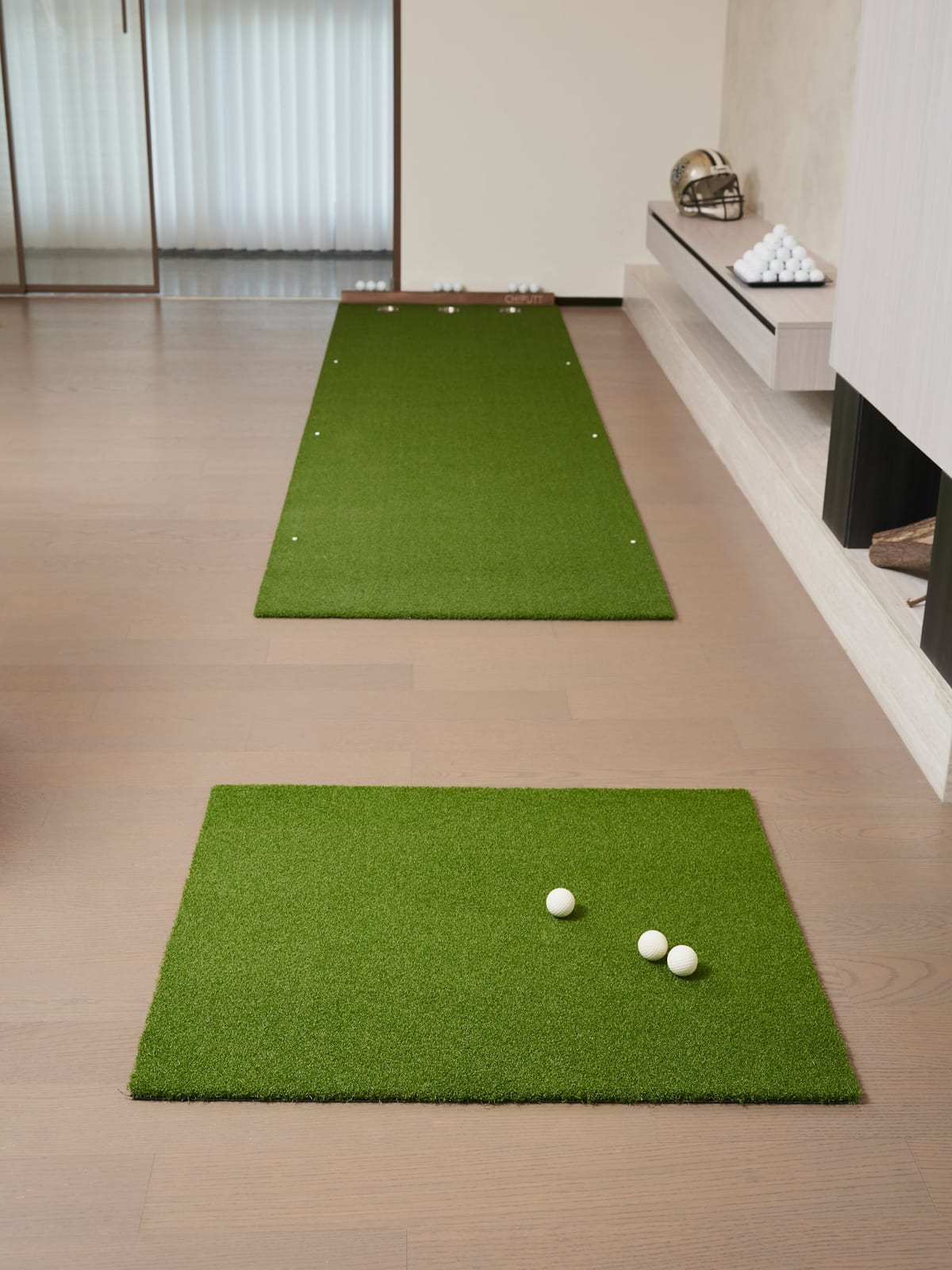 Two golf mats with balls on a wooden floor