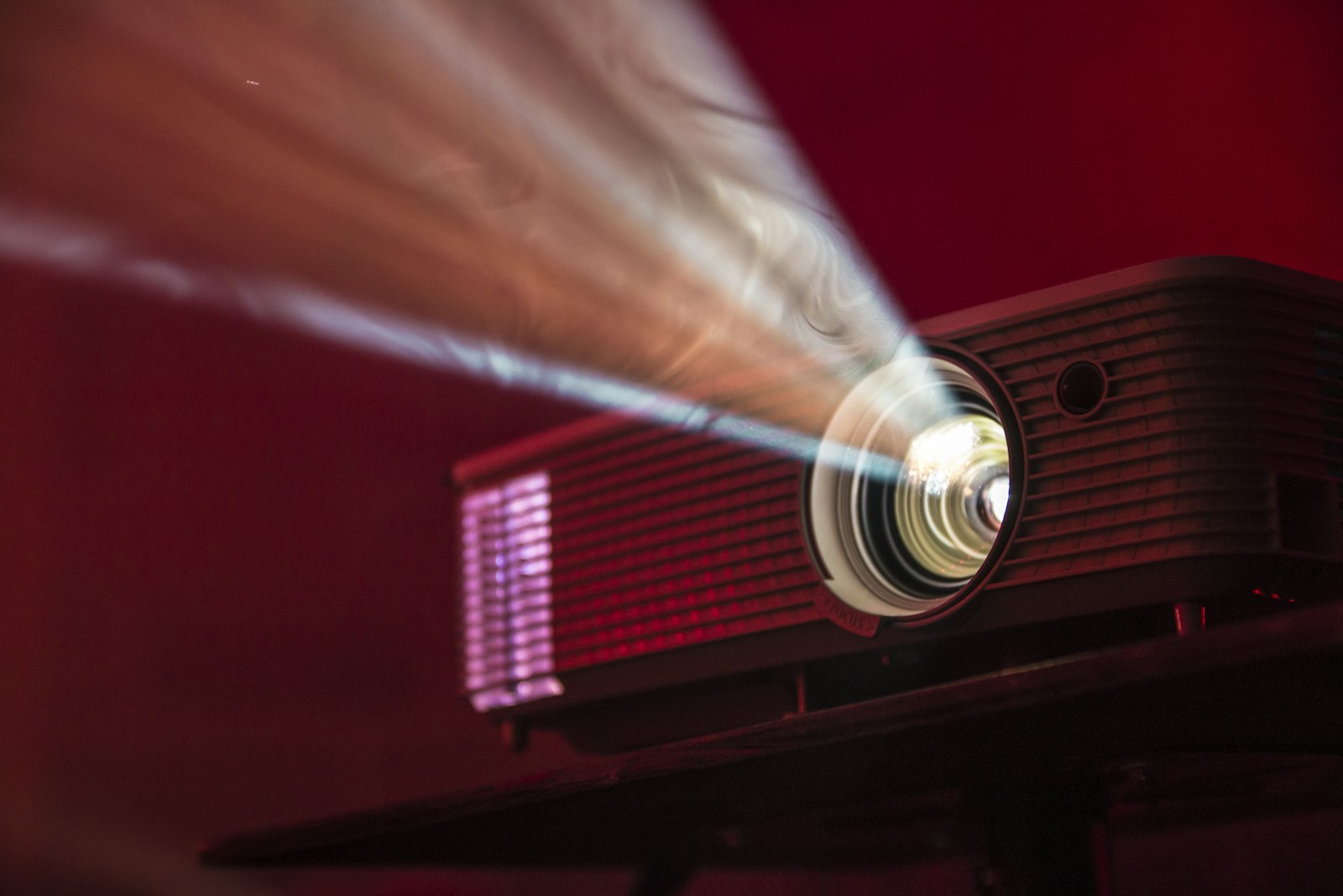 A turned-on LED projector on a table with its light beam visible