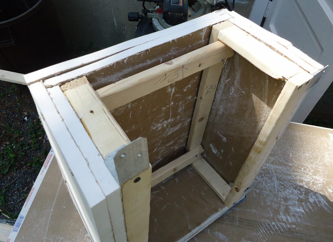 A three-sided tubular-pipe frame structure with L-bracket connectors, built inside a garage.