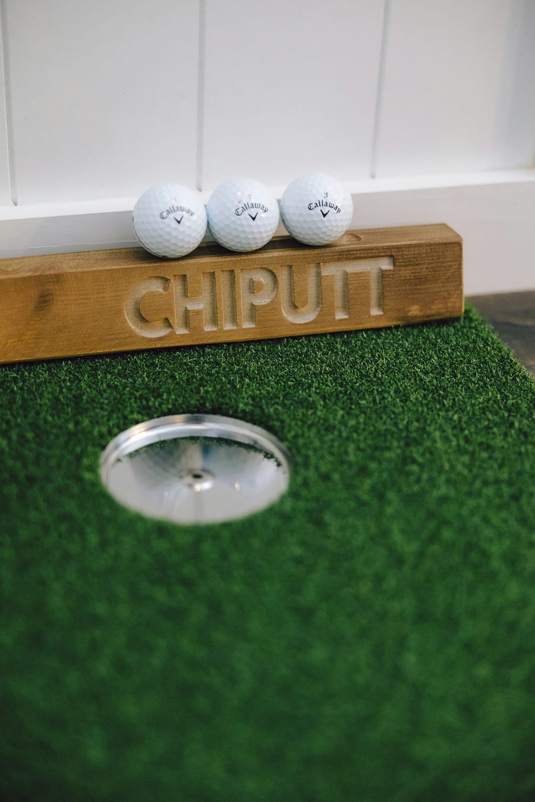 Three golf balls on a putting green near the hole