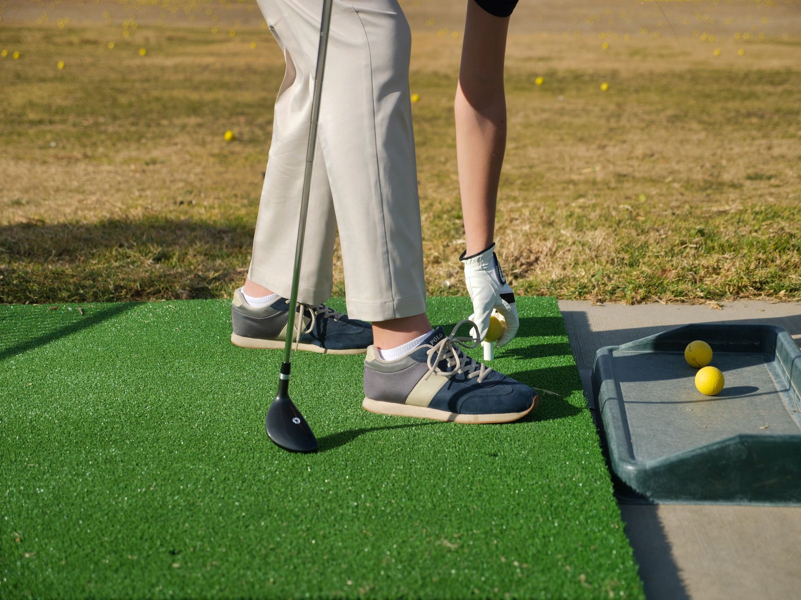 A person placing a golf ball on a tee before hitting into a net