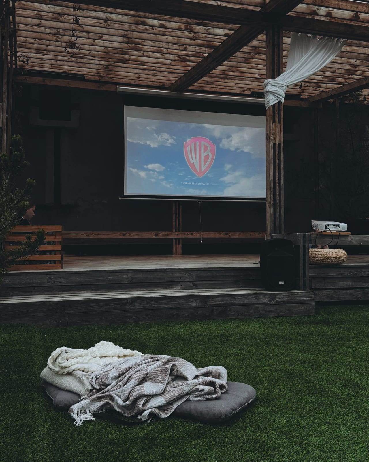 A projector filling a nearby screen at an outdoor movie setup