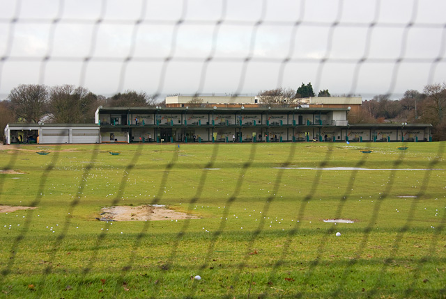 A golf driving range viewed through its protective catch netting