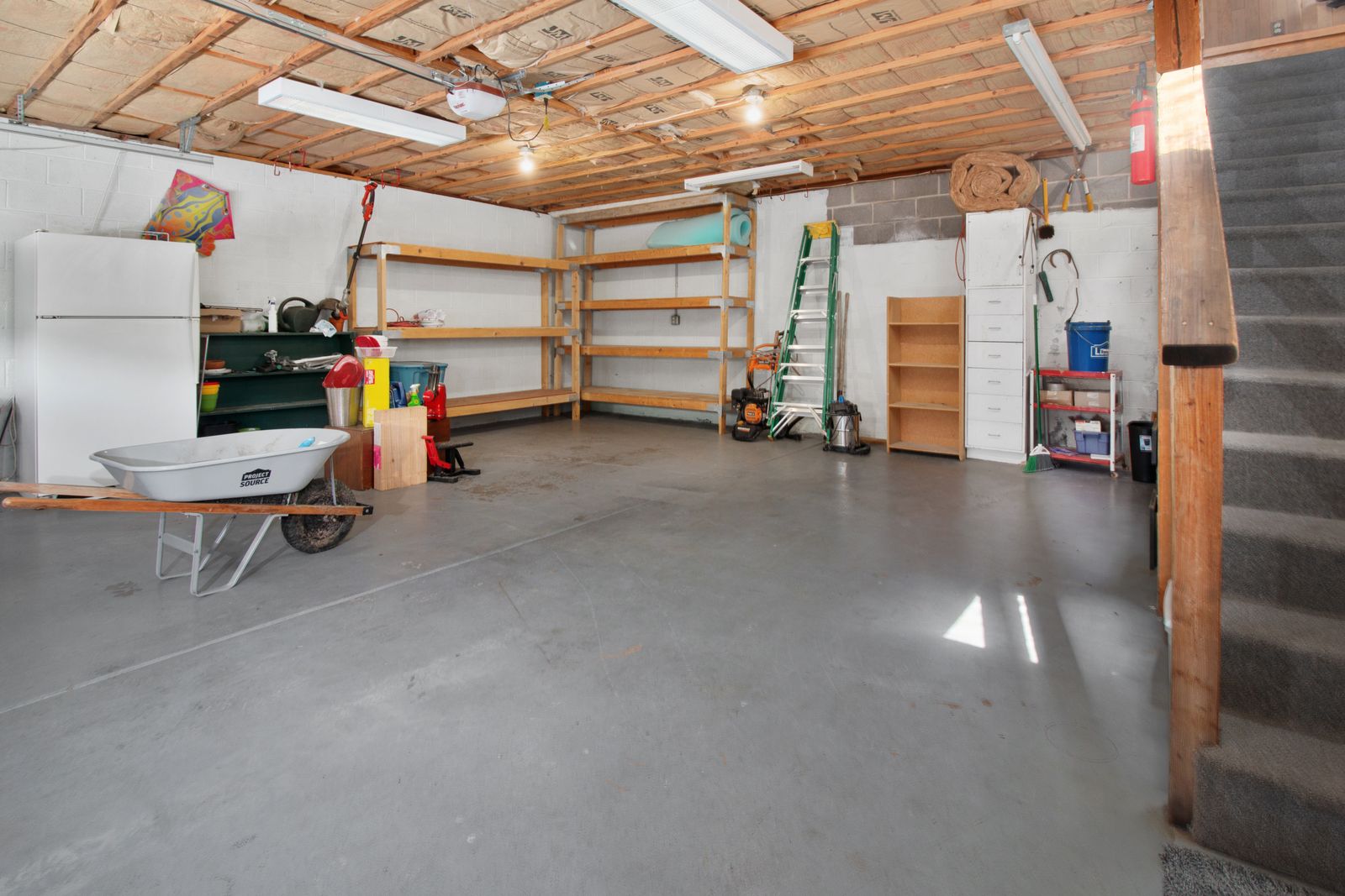 A spacious garage interior with storage shelves and tools along the walls