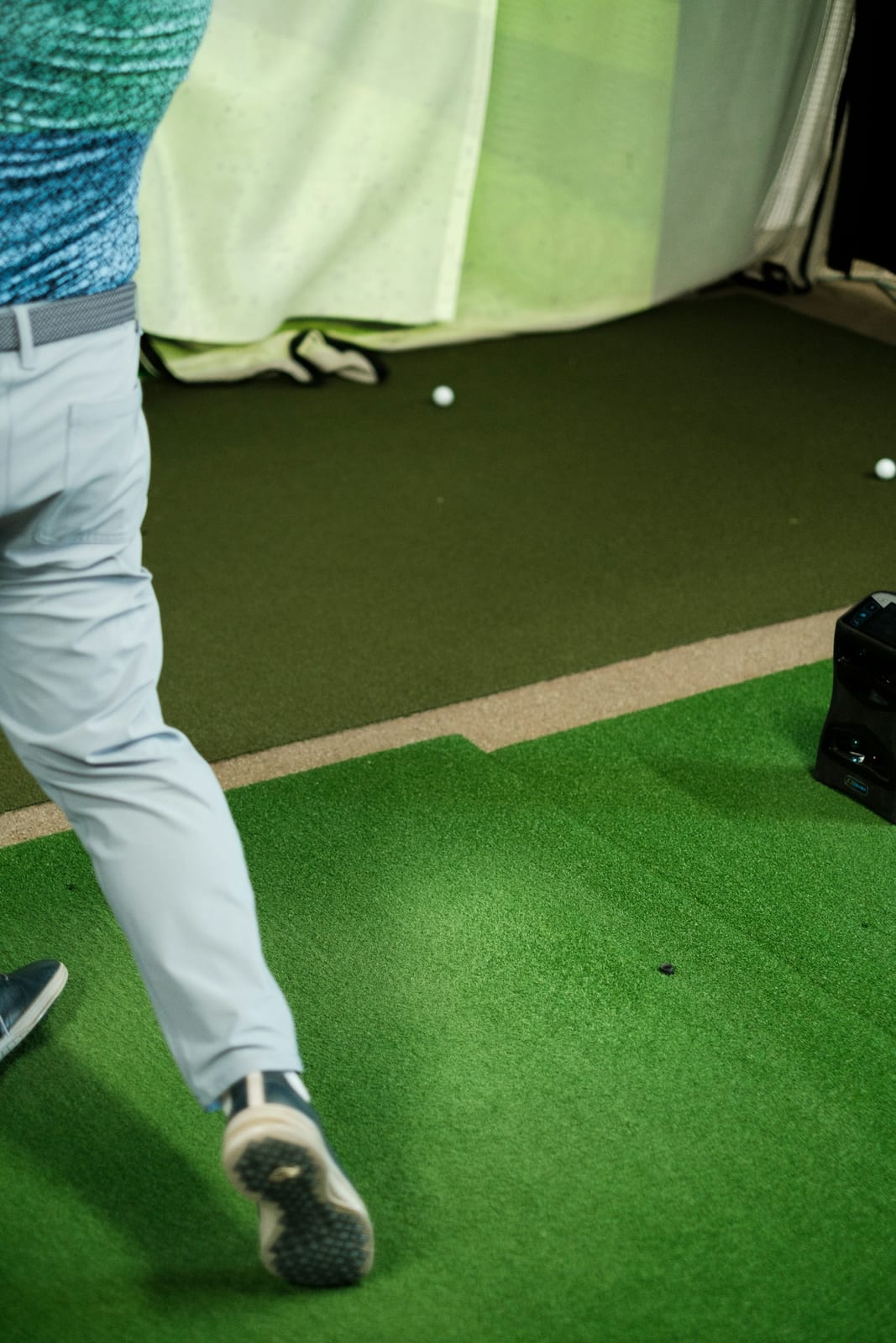 A man in a blue shirt and grey pants playing a round of golf on a course