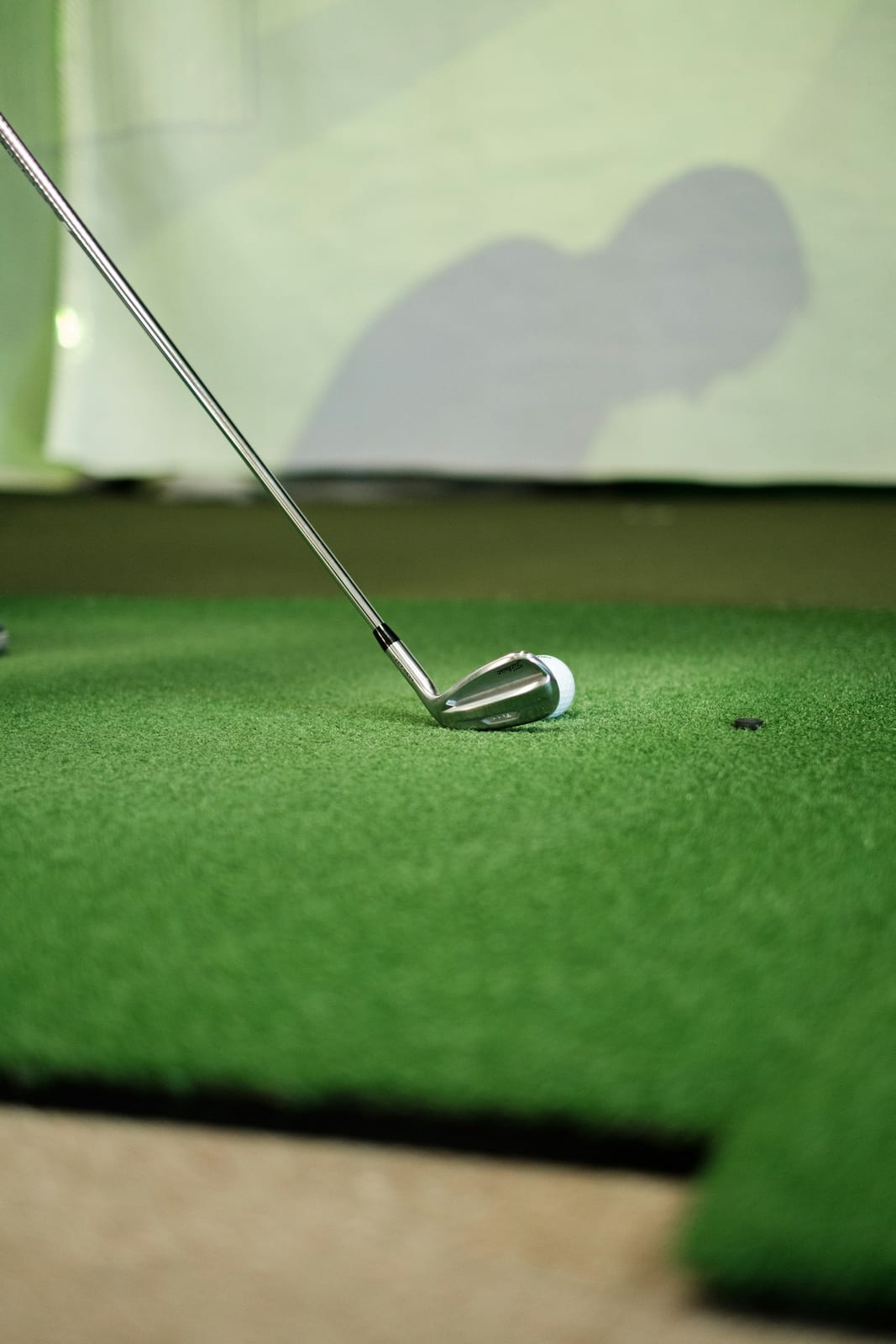 A golf ball and golf club resting on a putting green.