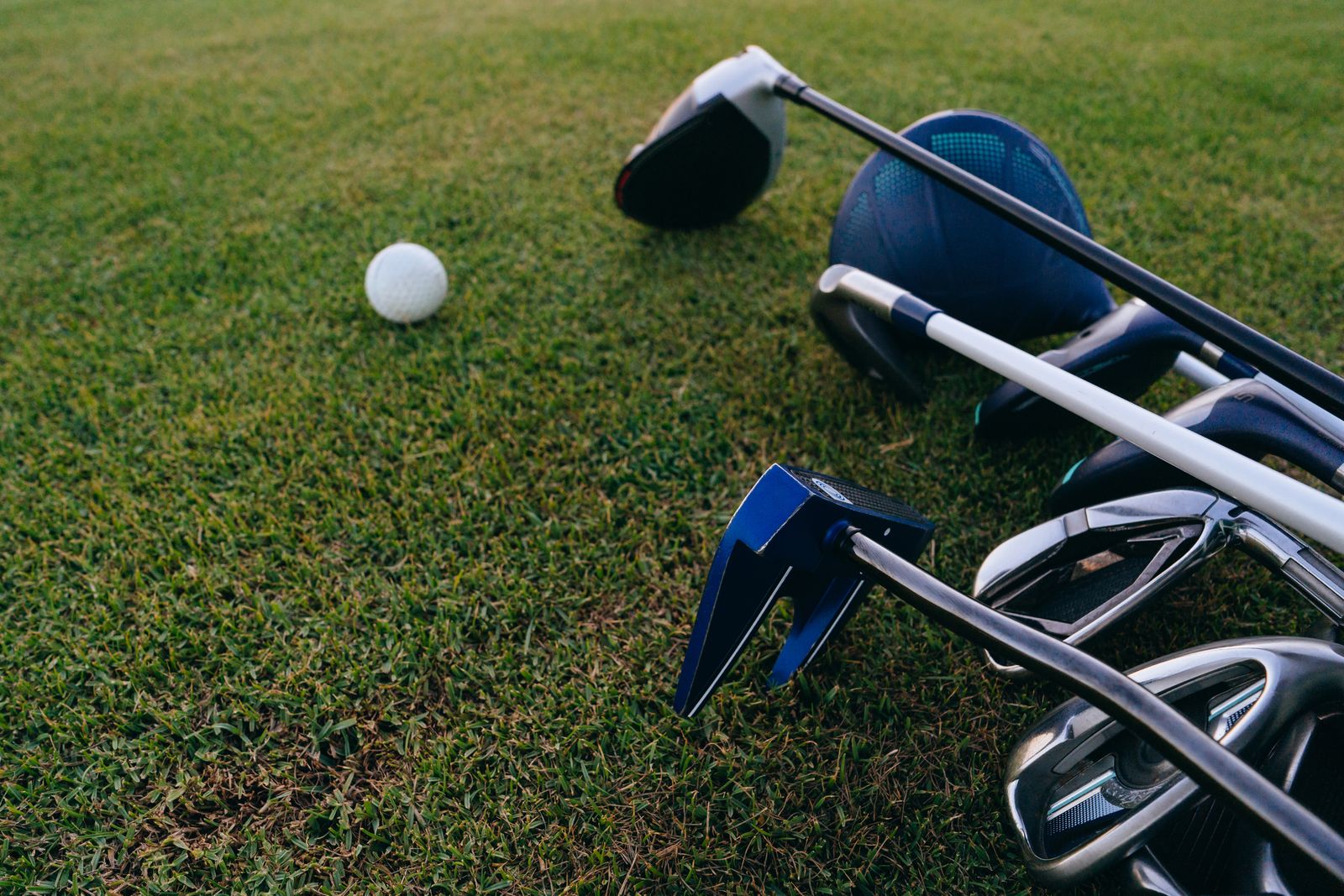 Close-up view of golf clubs and a ball on grass