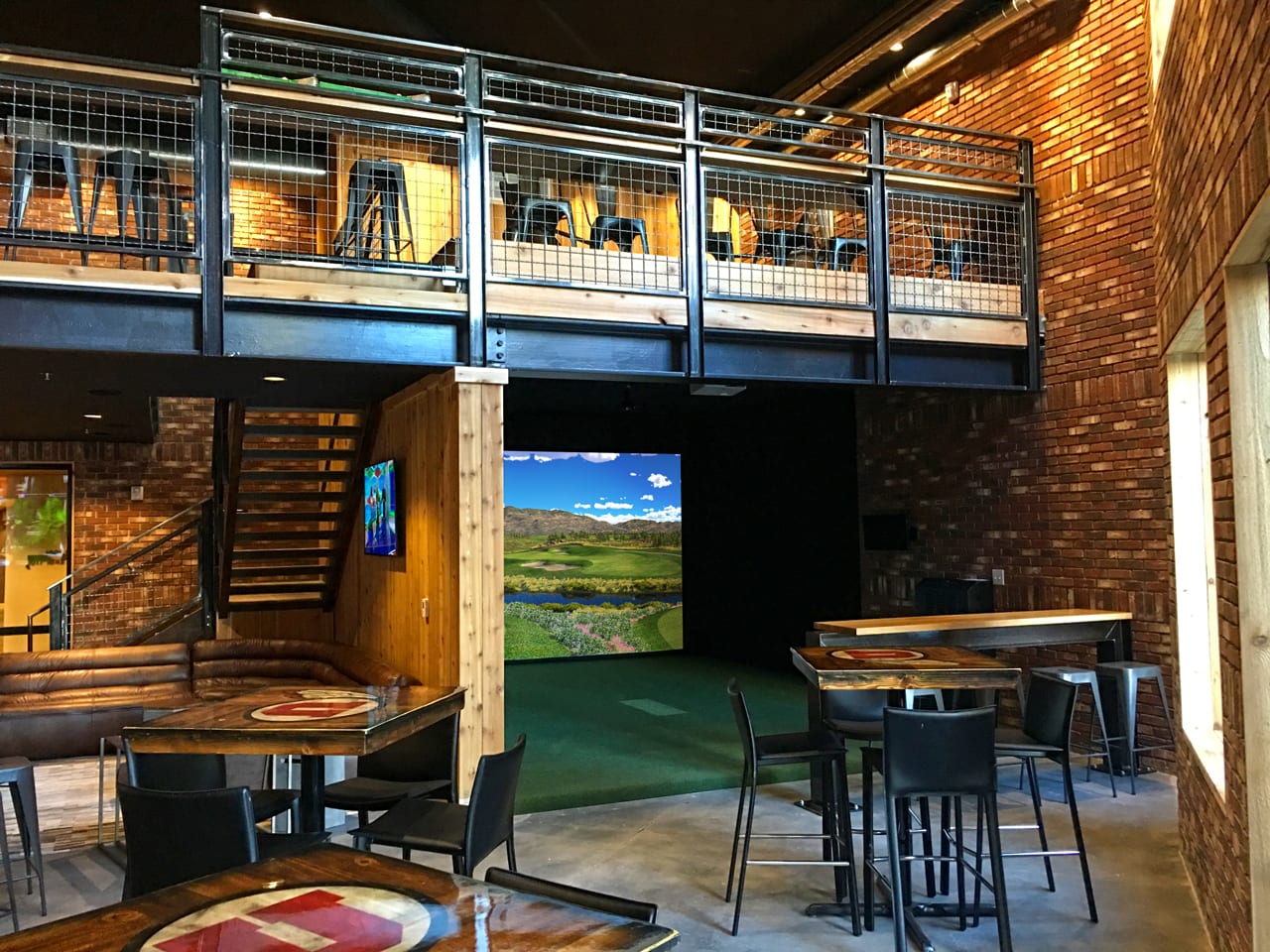 A residential indoor golf simulator bay with a hitting mat and projector screen