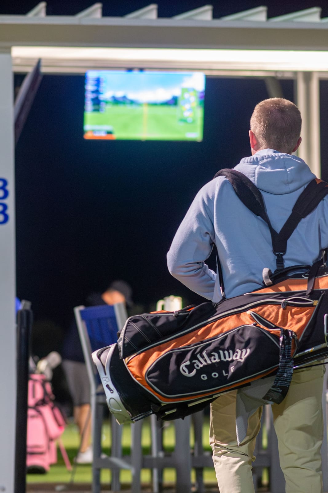 Golf practice at a driving range at night, illuminated by floodlights